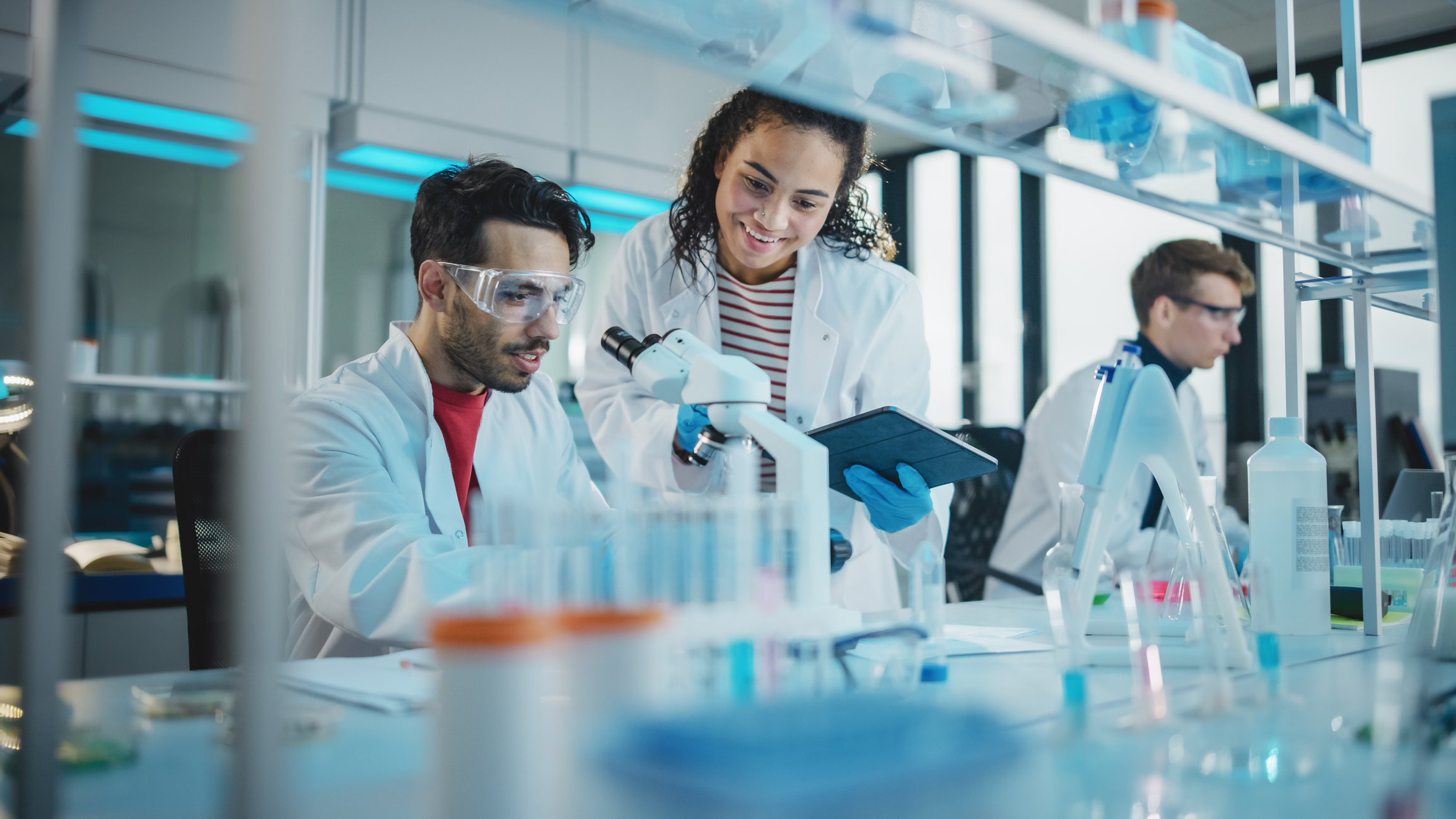 a group of scientists at a lab are looking through microscopes